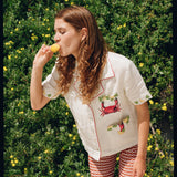 Woman eating ice cream leaning forward against hedge backdrop