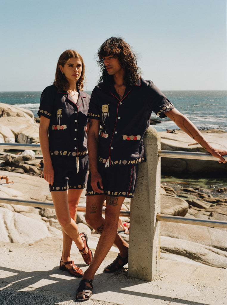 Woman gazing at man by the ocean while both wearing matching Tombolo Vongole linen set
