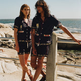 Male and female models on the beach wearing the full matching set with female model gazing at male model