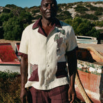 Male model standing among dry-docked boats wearing full 'Tombarolo' cabana set