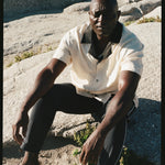 Male model wearing the cabana with the navy traveler pants sitting on a rock