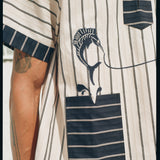 close-up of model in Tombolo striped pop-over shirt navy sleeve and pocket detailing with swordfish shown