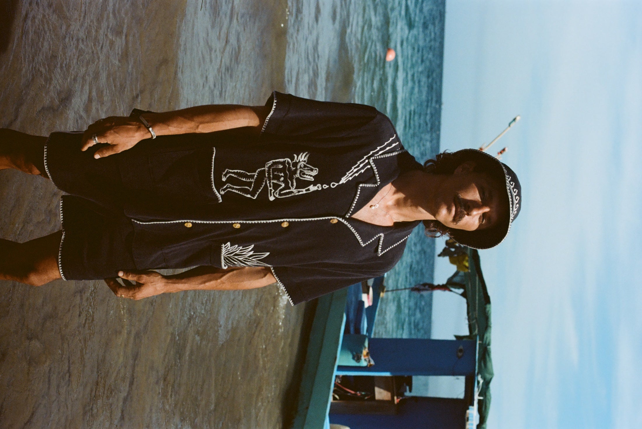Sideways image of male model with mustache wearing the full 'Agua Magica' Cabana set, including the bucket hat. 
