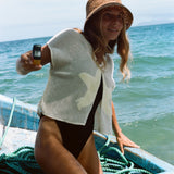 Woman wearing the 'Starfish Strut' Hand Towel Top over a black one piece bikini. She is holding a disposable camera in her right hand while she is moving on a boat. 