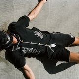 Male model laying on the beach wearing the full 'Agua Magica' Cabana set, with the bucket hat rest over his face to block the sun.