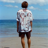 Image from behind of man on beach wearing the 'Mary Ball x Tombolo' Shirt with brown linen Easy Going Shorts.