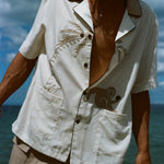 Closer image of male model at the beach, wearing his 'Monkey Business' Shirt slightly unbuttoned. 