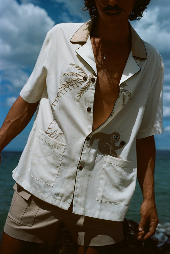 Closer image of male model at the beach, wearing his 'Monkey Business' Shirt slightly unbuttoned. 