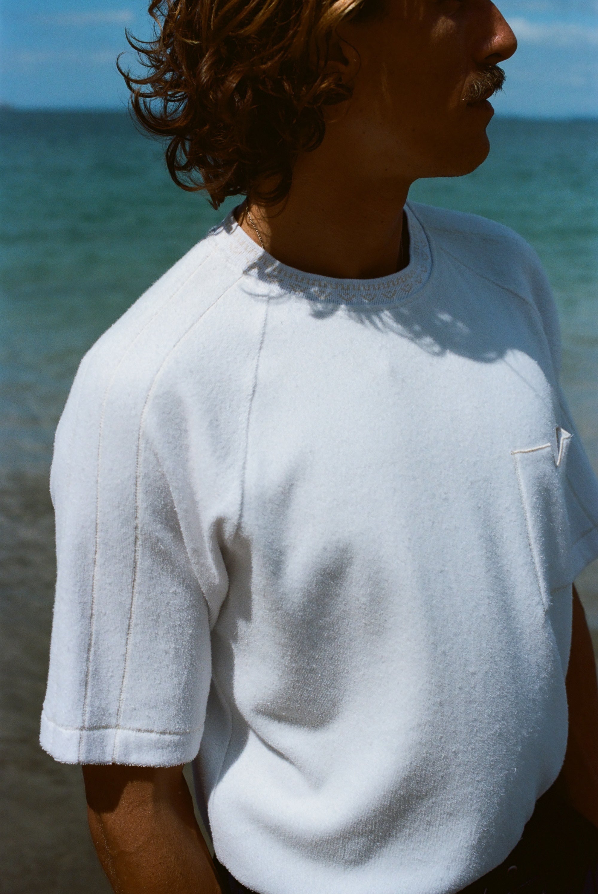 Cropped image of a man wearing the terry tee and looking off to the side.