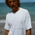 Brunette male model wearing the white terry tee and smizing at the camera. 