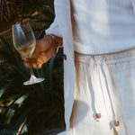 Close-up of man wearing the sand linen shorts while holding a glass of white wine. 