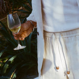 Close-up of man wearing the sand linen shorts while holding a glass of white wine. 