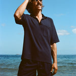 Man posed on the beach wearing navy 'TomPolo' with our navy Cabrisa swim trunks.
