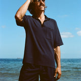 Man posed on the beach wearing navy 'TomPolo' with our navy Cabrisa swim trunks.