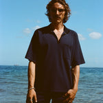 Man posed on the beach wearing navy 'TomPolo' with our navy Cabrisa swim trunks.
