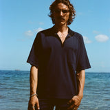Man posed on the beach wearing navy 'TomPolo' with our navy Cabrisa swim trunks.