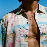 Close-up of a person wearing an open, colorful button-down shirt with abstract pink, blue, and yellow line art.