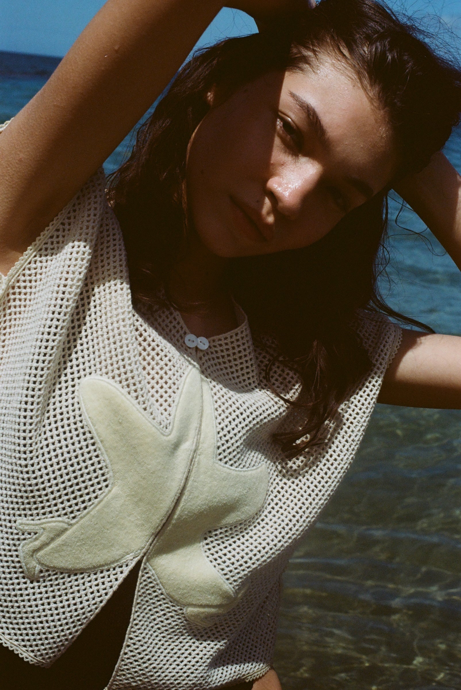 Close-up image of brunette female model posing with her arms above her head in the 'Starfish Strut' Hand Towel Top.