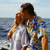 Male model wearing our 'Perfect Cast' Shirt, with his arm around a female model wearing the light blue sand dollar bikini shirt. Both are smiling while riding a boat.