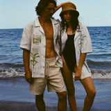 Man and woman standing close together on a beach, both wearing the 'Seasons of Change' by Mary Ball Shirts opened.
