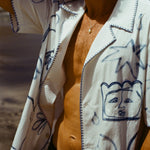 Close up of a man on the beach wearing the Mary Ball Artist Shirt unbuttoned.