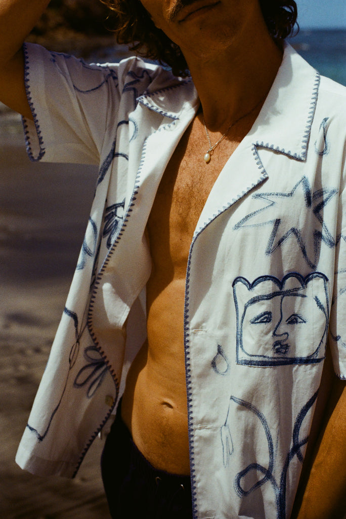 Close up of a man on the beach wearing the Mary Ball Artist Shirt unbuttoned.