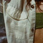 Close up of woman wearing a white button down shirt with pocket and spotted shell buttons.
