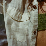 Close up of woman wearing a white button down shirt with pocket and spotted shell buttons.