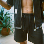 Cropped view of male model wearing the green terry cloth gambling themed set. Top is unzipped fully. 