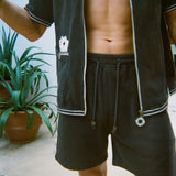 Cropped view of male model wearing the green terry cloth gambling themed set. Top is unzipped fully. 