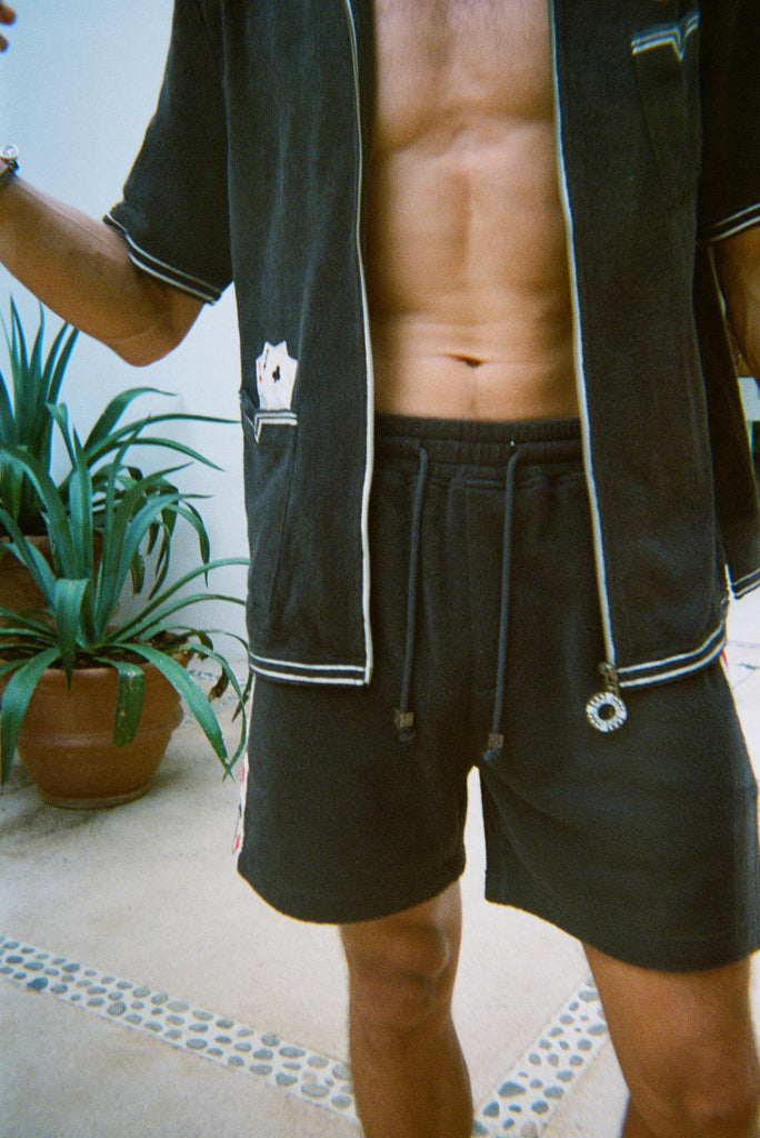 Cropped view of male model wearing the green terry cloth gambling themed set. Top is unzipped fully. 
