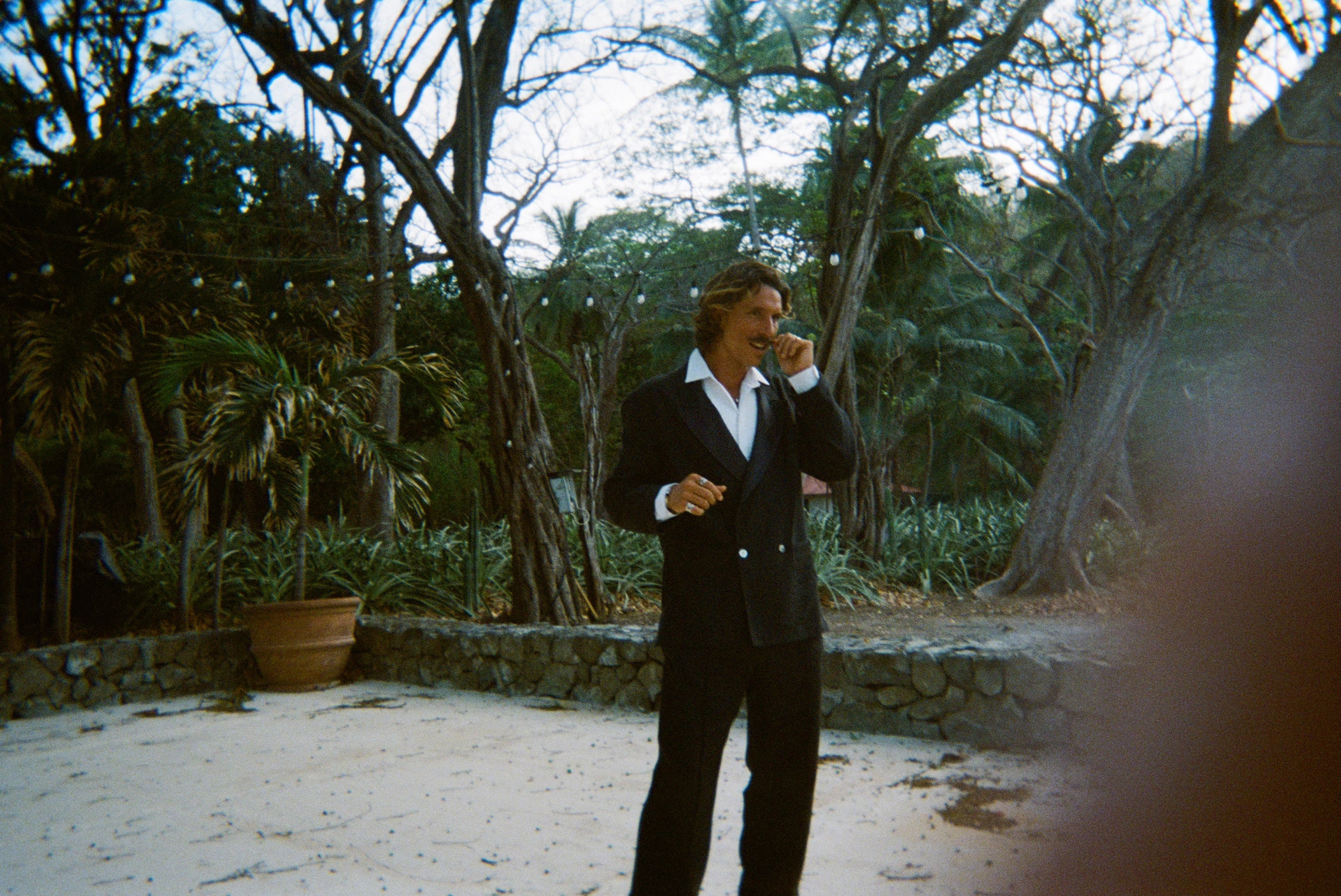 Man wearing the Easy-Going Tuxedo fully buttoned, and twisting the end of his mustache.