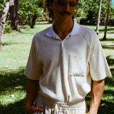 Man posed with hands in pockets, wearing the beige mesh 'TomPolo' and sand linen Easy-Going shorts.