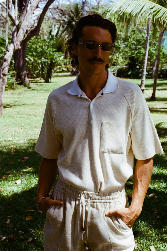 Man posed with hands in pockets, wearing the beige mesh 'TomPolo' and sand linen Easy-Going shorts.