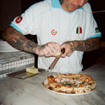 Man grating cheese over a freshly made pizza. 