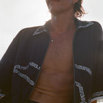 Brunette man wearing the black short-sleeve terrycloth 'Beach Break' Cabana fully unzipped, shown from the waist up.