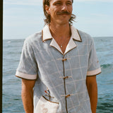 Male model smiling on boat, wearing 'The Explorers Club' Expedition Cabana and swim trunks.