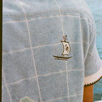 Close up of the small sailboat stitched near the upper right shoulder.