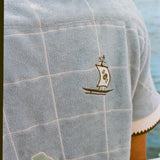 Close up of the small sailboat stitched near the upper right shoulder.