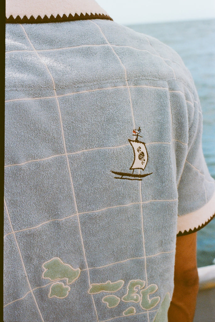 Close up of the small sailboat stitched near the upper right shoulder.