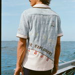 Male Model with long hang is showing off the backside of 'The Explorers Club' Expedition Cabana with swim trunks on a boat.