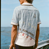 Male Model with long hang is showing off the backside of 'The Explorers Club' Expedition Cabana with swim trunks on a boat.