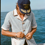 Male model wearing 'The Explorers Club' 6-Panel Souvenir Cap (Wool) and buttoning up his 'The Explorers Club' Expedition Cabana.