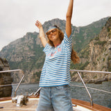Woman standing on a boat wearing the blue striped Le Sirenuse terry cloth t-shirt.