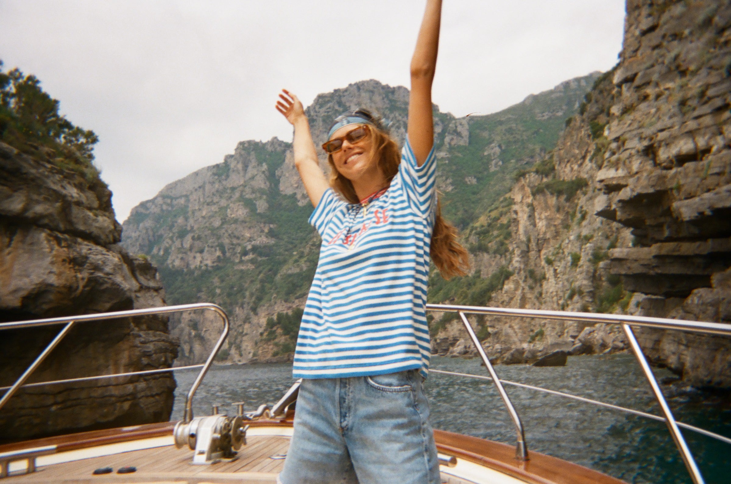 Woman standing on a boat wearing the blue striped Le Sirenuse terry cloth t-shirt.