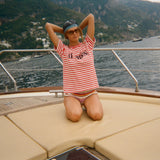 Woman in a striped Le Sirenuse shirt and sunglasses on a boat with a scenic background