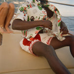 Man wearing a colorful shirt and sunglasses with a scenic coastal background