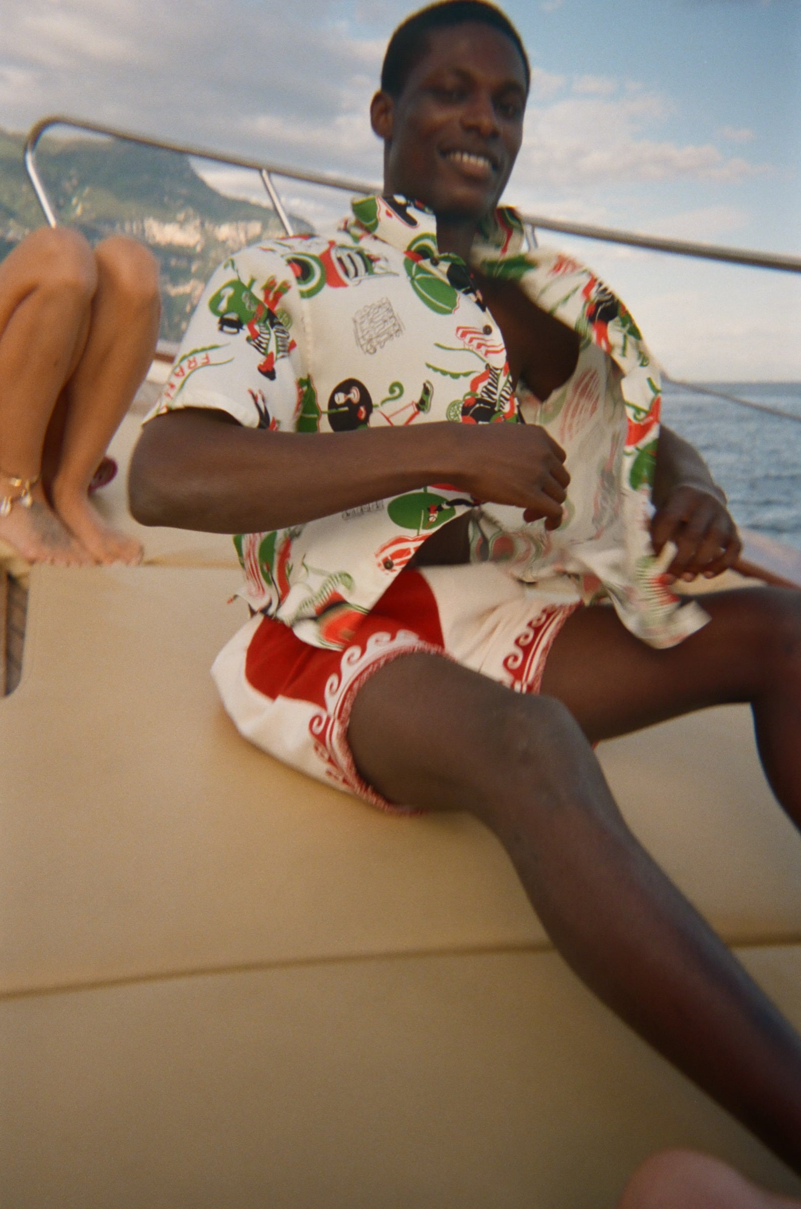 Man wearing a colorful shirt and sunglasses with a scenic coastal background