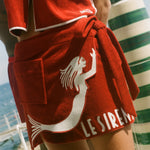 Woman wearing matching Le Sirenuse hand towel set, standing in front of the ocean. 