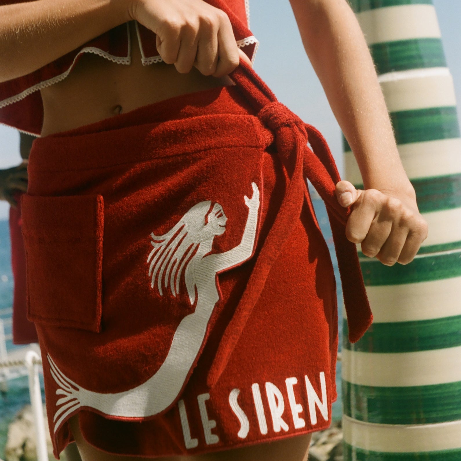 Woman wearing Le Sirenuse wrap towel skirt, mid-tie. 